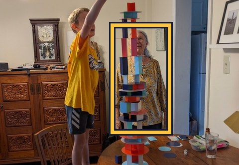 Woman partly hidden behind a child's toy tower, outlined in gold.