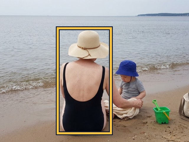 The same woman seated on the beach with her back to the camera; no face visible.